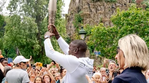 Photo: X/ @Paris2024 : Olympic medalist Souleymane Cissokho held the Olympic torch during the torch relay at Buttes-Chaumont in Paris.